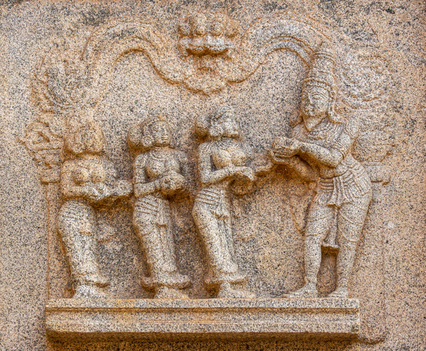 Hampi, Karnataka, Indie - 4 listopada 2013: Świątynia Hazara Rama. Zbliżenie beżowe kamienne rzeźby zniszczone 3 kobiety przynoszące jedzenie do królewskiego. - Zdjęcie, obraz