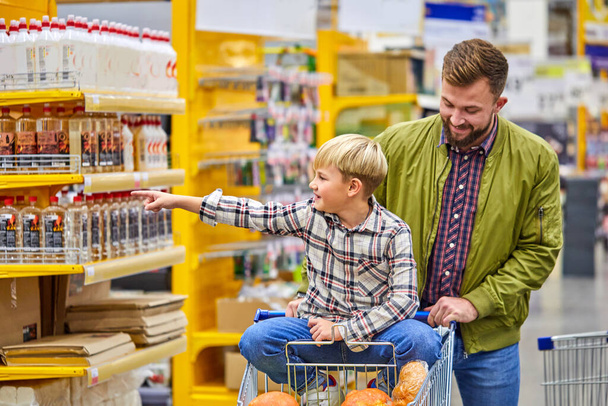 positive child boy enjoys shopping time with father in supermarket - Фото, изображение
