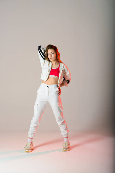 Cute teen dancing hip hop in reflective pants, in a Studio with neon lighting. Dance color poster. - Photo, image
