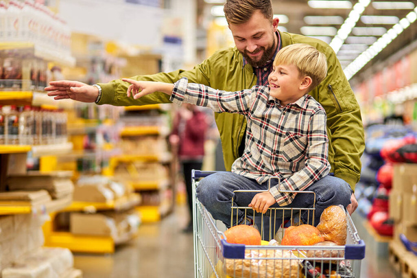 kid boy point finger at side in store during shopping with father - Foto, immagini