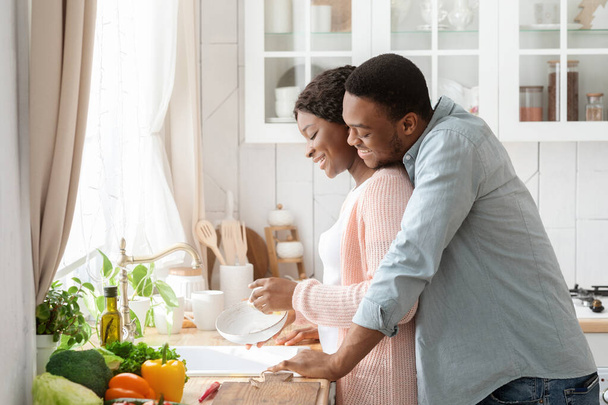 Romantický černošky pár úklid nádobí a spojování dohromady v kuchyni - Fotografie, Obrázek