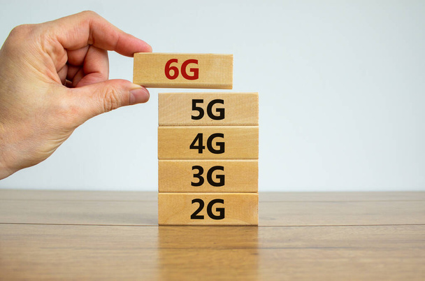 6G network evolution symbol. Hand holding a wooden block with 6g symbol. 2G, 3G, 4G, 5G words. Copy space. Beautiful white background. Technology, business, communication and 6G concept. - Foto, Imagem
