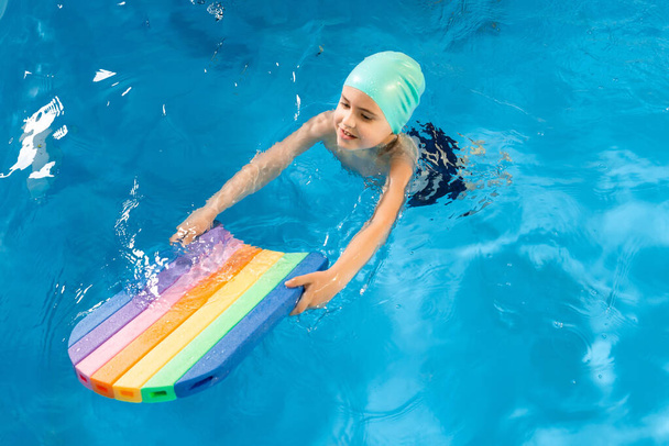 Schwimmkurs. Nahaufnahme von Kindern, die Flatterkick mit Kickboard im Schwimmbad üben - Foto, Bild