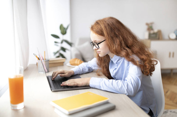 Lány ül az asztalnál, laptoppal, gépelés billentyűzeten - Fotó, kép