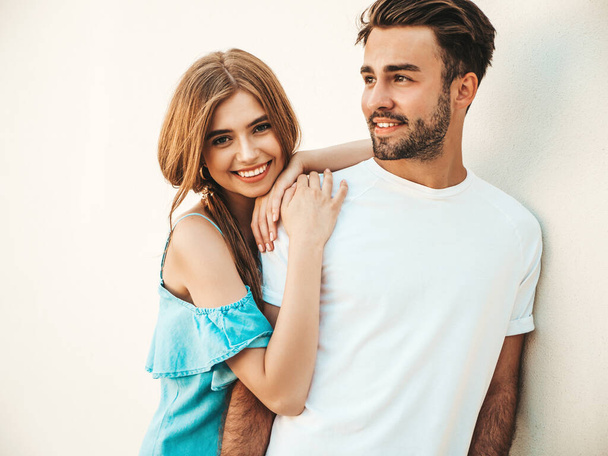 Portrait of smiling beautiful woman and her handsome boyfriend. Model in casual summer jeans dress. Happy cheerful family. Female having fun. Couple posing near wall - Foto, Imagem