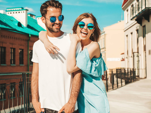 Portrait of smiling beautiful woman and her handsome boyfriend. Model in casual summer jeans dress. Happy cheerful family. Female having fun. Couple posing on the street background in sunglasses - Photo, Image