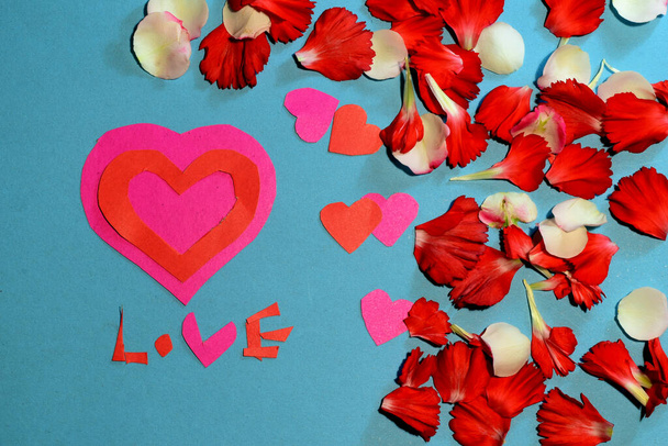 La tarjeta de felicitación azul de San Valentín tiene un corazón rojo síntoma de amor y la palabra amor en el centro de la hoja. - Foto, imagen