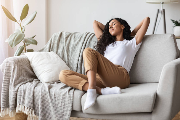 Беззаботная молодая женщина отдыхает дома на диване - Фото, изображение