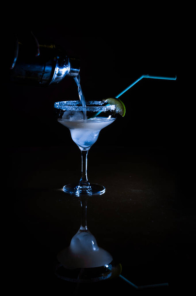 Охолоджений коктейль змішаний з текілою і лимонним соком, залитим з коктейлю шейкера на кубиках льоду в склянці Маргарити, що має сіль на краю і прикрашений лимонно-блакитною соломою в різдвяну ніч
 - Фото, зображення