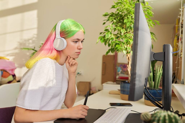 Girl teenager artist in headphones drawing on computer using graphics tablet - Foto, Imagen