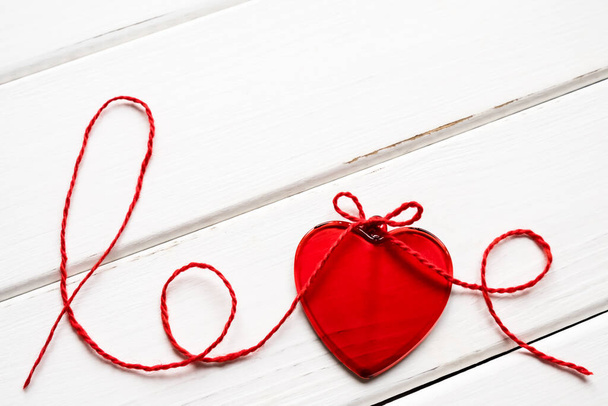 Valentine's day concept. Red heart and word love made from woolen rope on wooden background with copy space. - Foto, imagen
