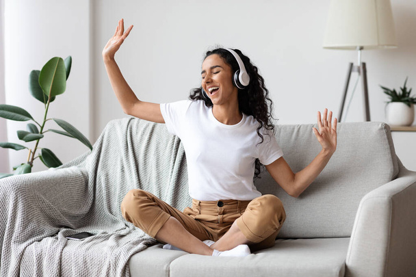 Carefree woman listening to music and singing, using headphones - Фото, изображение