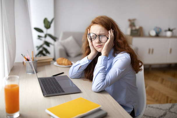 Zmęczona dziewczyna siedzi przy biurku z laptopem - Zdjęcie, obraz