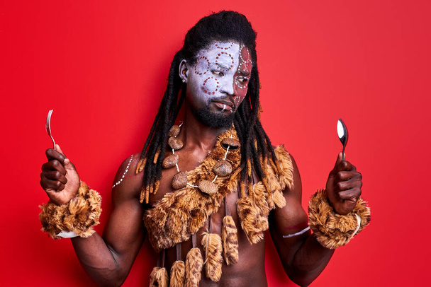 african aborigen male holding spoon and fork in hands, choosing - 写真・画像