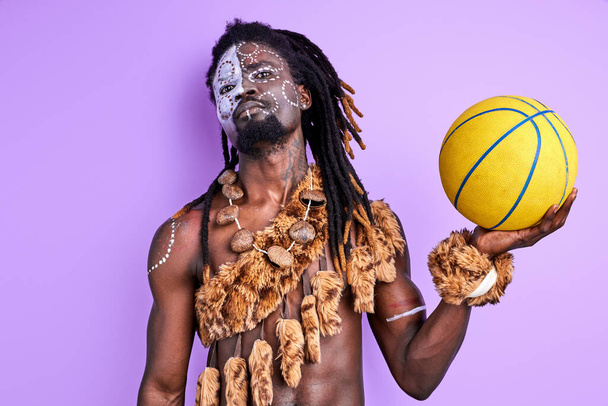 confident afro american pagan male with national make-up holding basketball ball in hands - Fotografie, Obrázek