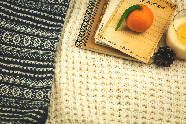 Winter background with knitted sweaters, books and tangerines, home comfort concept on cozy holidays, copy space photo - Photo, Image
