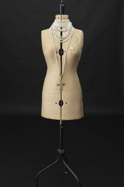 Un maniquí de costureras vintage con collares de pera envueltos alrededor de su cuello - Foto, Imagen
