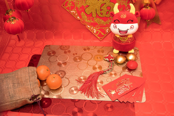 Σύνθεση κινεζικής Πρωτοχρονιάς με τραπέζι και κόκκινο φόντο με κόκκινες και ασημένιες διακοσμήσεις, τραπεζομάντηλα και βόδι και μανταρίνια - Φωτογραφία, εικόνα