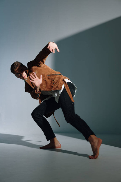 Чоловік в коричневій куртці піднімається похилою підлогою і жестами своїми руками
 - Фото, зображення