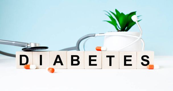 The word DIABETES is written on wooden cubes near a stethoscope on a wooden background. Medical concept - Valokuva, kuva