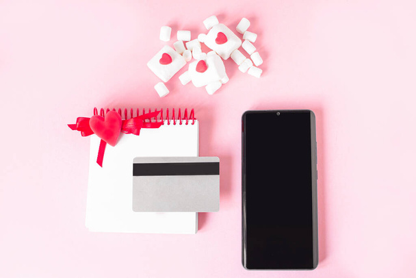 Valentine Day online Shopping. Credit card, smartphone, notepad, marshmallows, red hearts. Romantic shopping for wedding, womens day, buying gifts Valentines Day for lovers. Seasonal Holiday sale. - Fotografie, Obrázek
