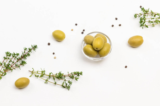 Green olives and thyme sprigs on white background. Copy space. White background. Flat lay - Foto, Imagen