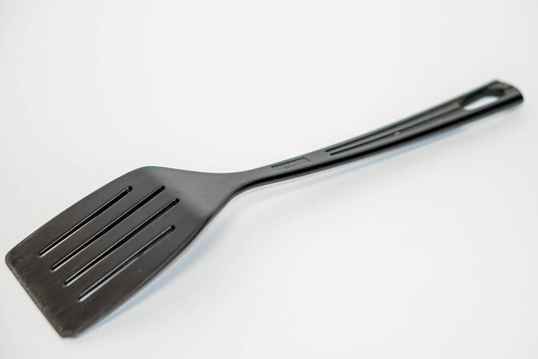 Schwarzer Kunststoff-Küchenspachtel isoliert auf weißem Hintergrund - Foto, Bild