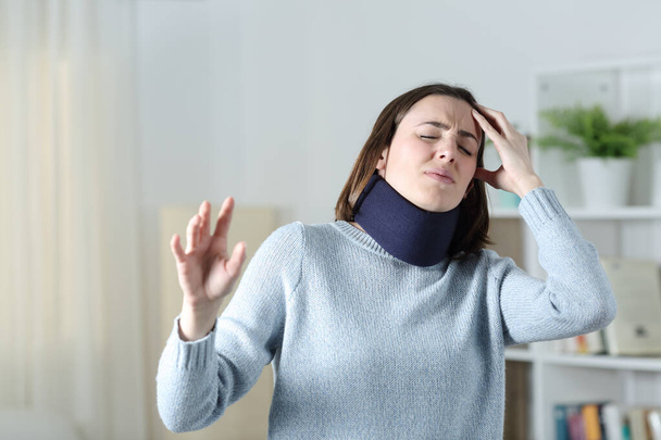 Dizzy woman wearing neck brace suffering standing at home - Фото, изображение