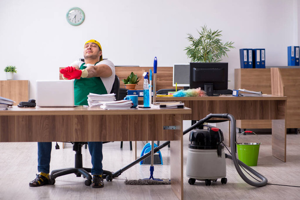 Jonge mannelijke aannemer schoonmaken van het kantoor - Foto, afbeelding