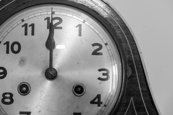 Fekete-fehér fénykép egy antik óráról, amin 12 oklus van. - Fotó, kép