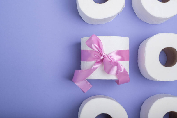 Roll of toilet paper wrapped in a gift bow. on a purple background. top view. High quality photo - Valokuva, kuva
