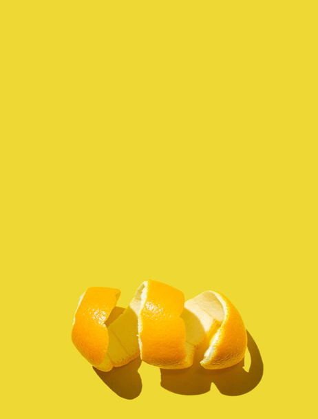 Citrusfélék koncepciója friss narancshéj spirállal, élénk sárga háttérrel. Minimális stílus lakás feküdt, szöveges hely - Fotó, kép