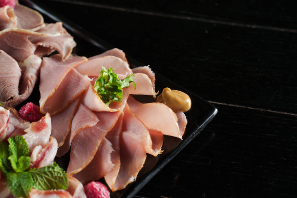 Charcuterie board close-up com carne curada. Carne fumada na placa preta - Foto, Imagem