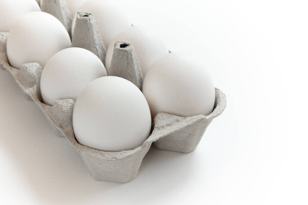 Huevos de pollo blancos en caja. Caja de cartón con huevos de gallina sobre fondo blanco. - Foto, imagen