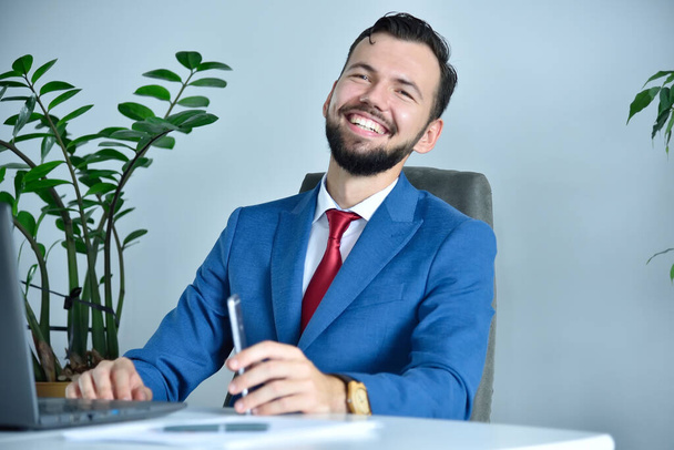Happy bearded businessman sitting in modern office. Occupation and worker concept. - Foto, immagini