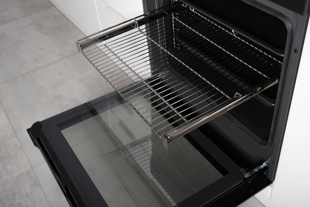 New modern electric oven built in black with screen, convention and grill, empty and open. Telescopic guides. Scandinavian loft style in a white minimalistic kitchen. - Photo, Image