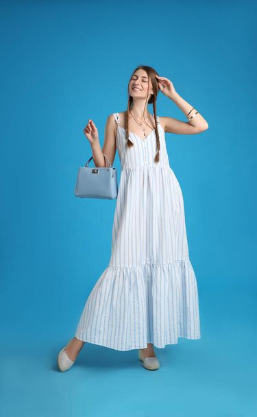 Beautiful young woman with stylish bag on light blue background - Photo, image