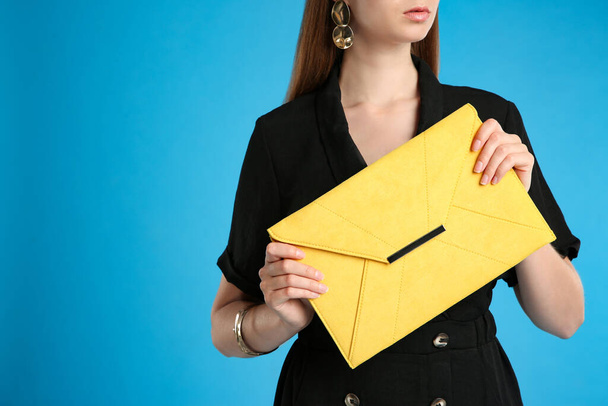 Young woman with stylish yellow bag on light blue background, closeup. Space for text - Foto, Imagen