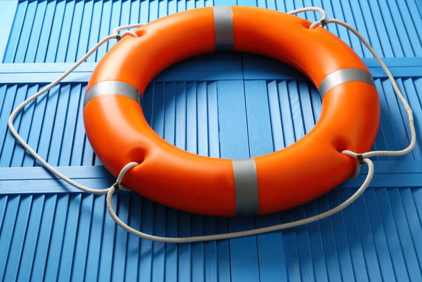 Orange lifebuoy on blue wooden background, closeup. Rescue equipment - Photo, image