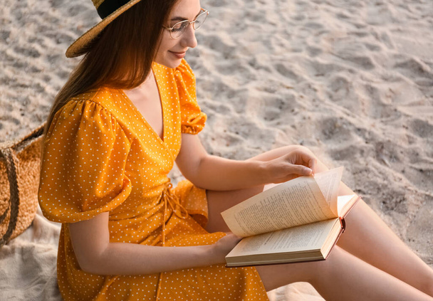 Young woman reading book on sandy beach - Fotó, kép