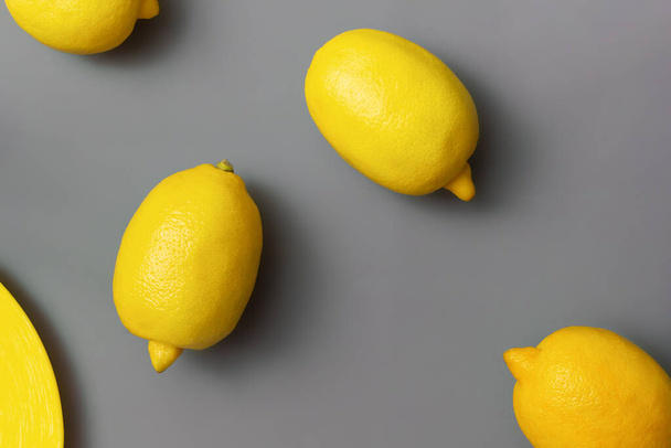 Gelbe Zitronen auf grauem Hintergrund. Farben des Jahres 2021 Pantone Illuminating und Ultimate grau, flache Lage - Foto, Bild