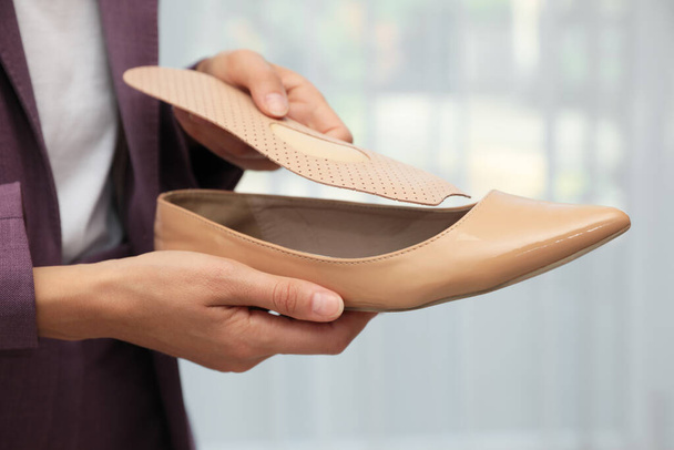 Woman putting orthopedic insole into shoe indoors, closeup. Foot care - Photo, Image