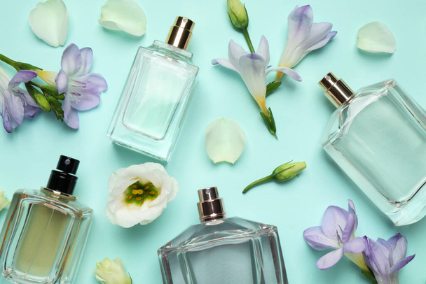 Flat lay composition of different perfume bottles and flowers on cyan background - Foto, Bild