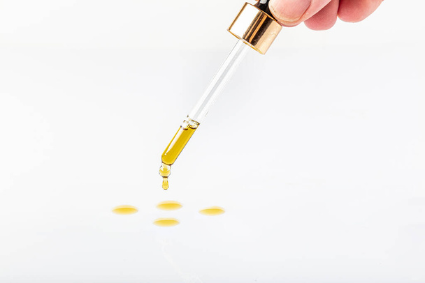 Pipette dropping black seed oil onto white background. Organic nigella sativa oil popular in the Middle and Far East. Also referred to as black cumin oil or black caraway oil. - Photo, Image