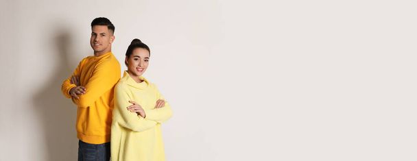 Happy couple wearing yellow warm sweaters on white background - Foto, imagen