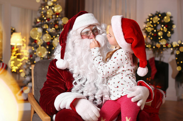 Santa Claus and cute little girl in room decorated for Christmas - Fotó, kép
