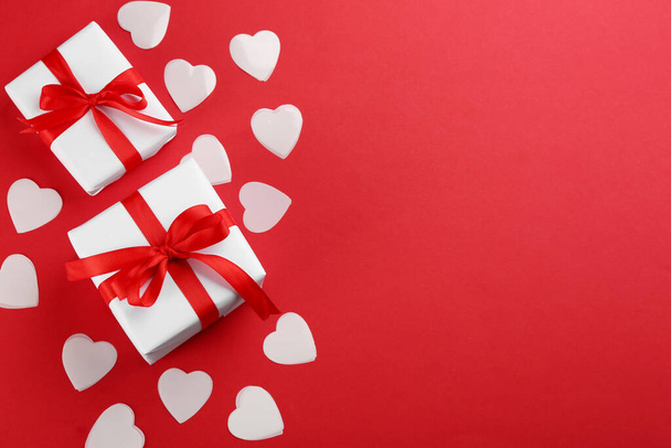 Hermosas cajas de regalo, corazones sobre fondo rojo, piso con espacio para el texto. Celebración de San Valentín - Foto, imagen