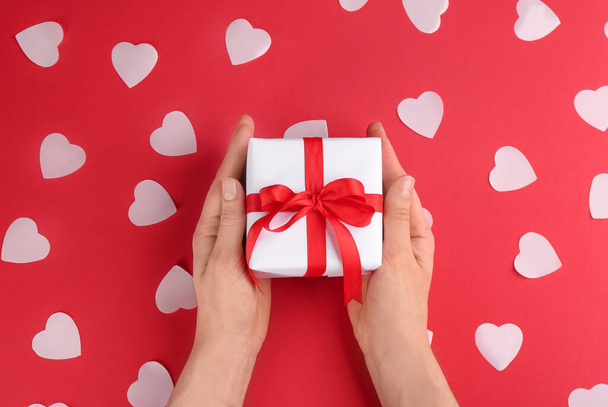 Woman holding gift box on red background, top view. Valentine's Day celebration - Foto, afbeelding