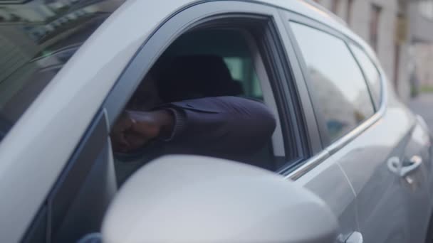 Feliz negro afro-americano sentado no banco dos motoristas em seu novo carro elétrico e mostrando o polegar para cima - Filmagem, Vídeo