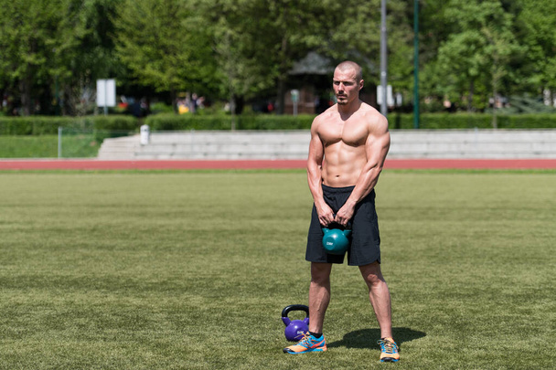 Man Working Out With Kettle Bell Outdoors - Bodybuilder Doing Heavy Weight Exercise With Kettle-bell - Photo, image